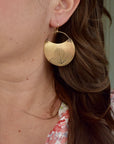Model wearing large handmade brass hydrangea crescent dangle earrings, statement botanical nature jewelry crafted in Vermont