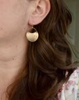 Model wearing tiny handmade brass hydrangea crescent dangle earrings, delicate botanical nature jewelry handcrafted in Vermont