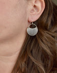 Model wearing medium handmade silver hydrangea crescent dangle earrings, rustic botanical jewelry handcrafted in Vermont