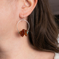 Model wearing handmade sterling silver amber and turquoise nugget hoop earrings with brass wire wrapping, artisan nature inspired gemstone jewelry handcrafted in Vermont