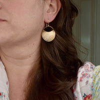Model wearing medium handmade brass hydrangea crescent dangle earrings, rustic botanical jewelry handcrafted in Vermont