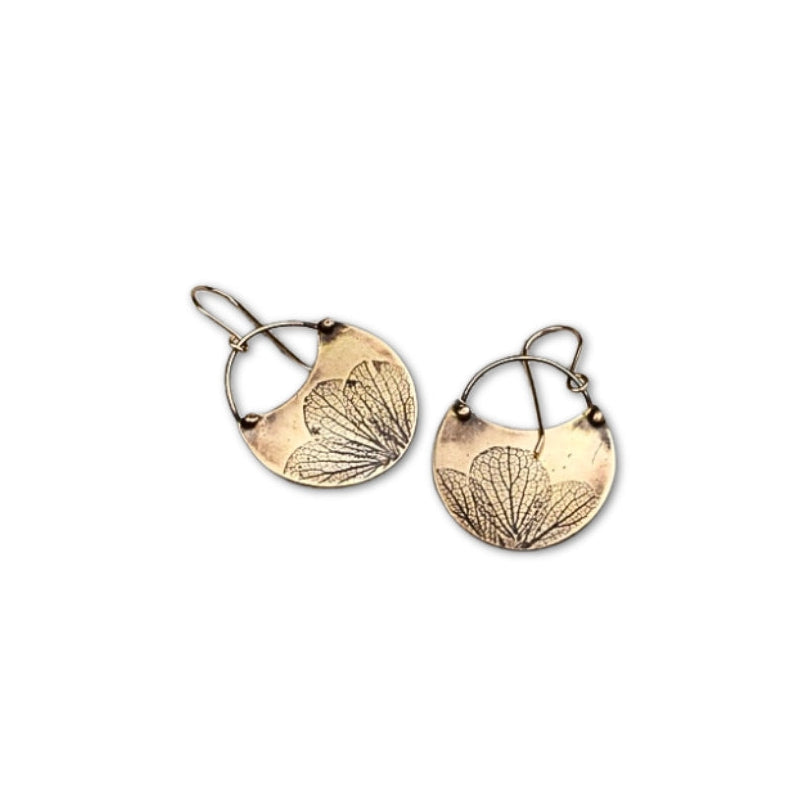 Overhead view of small handmade jeweler's brass hydrangea flower impression crescent dangle earrings, artisan botanical jewelry crafted in Vermont