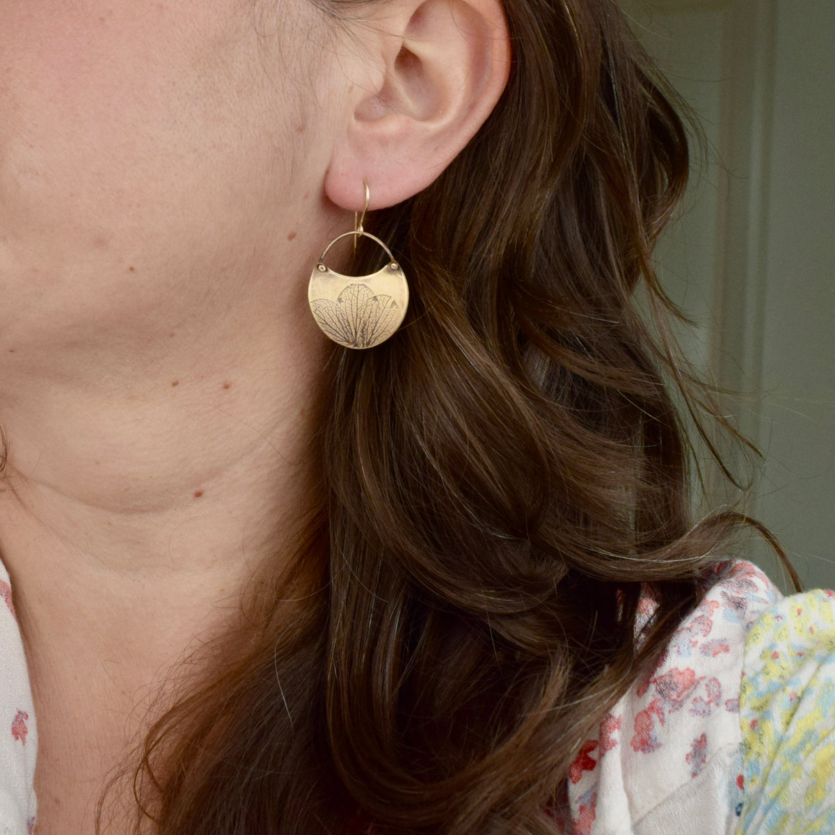 Model wearing tiny handmade brass hydrangea crescent dangle earrings, delicate botanical nature jewelry handcrafted in Vermont