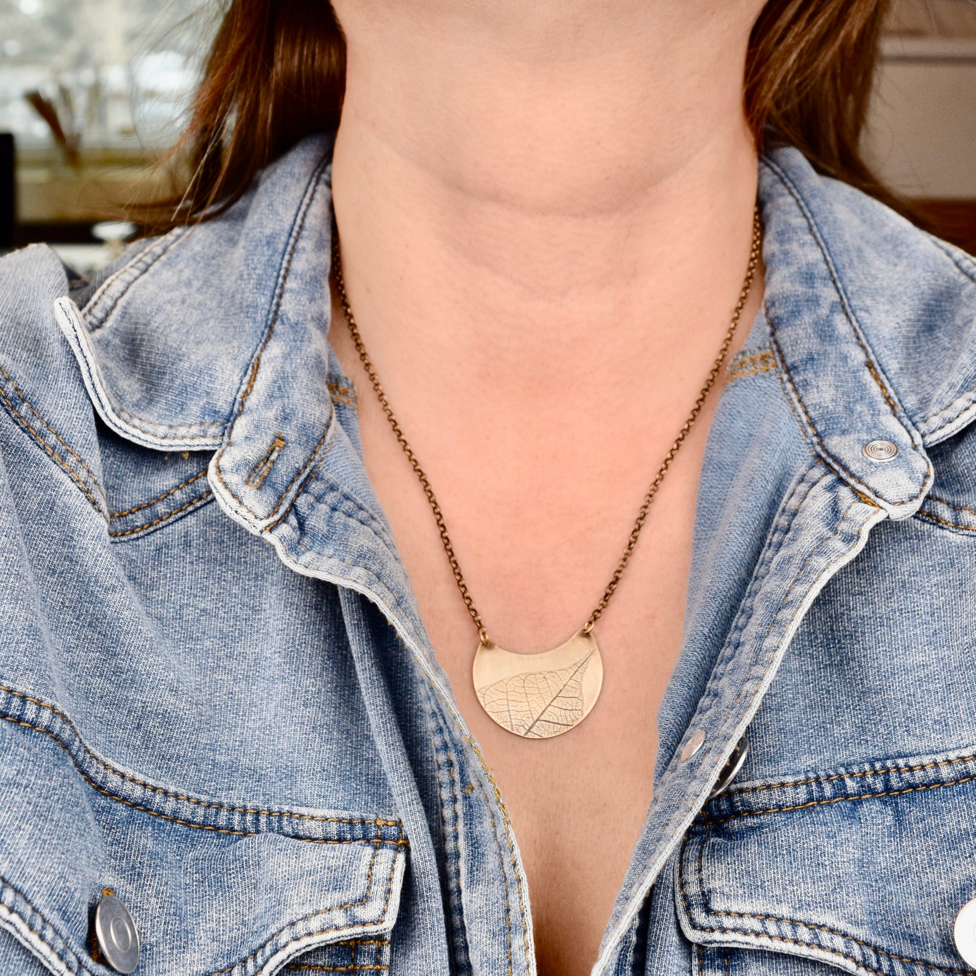 Model wearing medium jeweler's brass crescent leaf necklace, handmade botanical jewelry