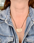 Model wearing medium jeweler's brass crescent leaf necklace, handmade botanical jewelry