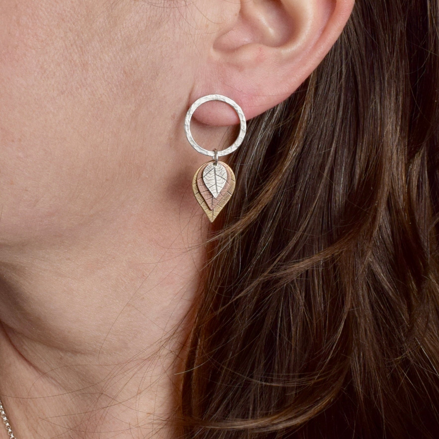 Close-up detail of hammered square rod circle with brass, copper, and sterling silver leaf dangles