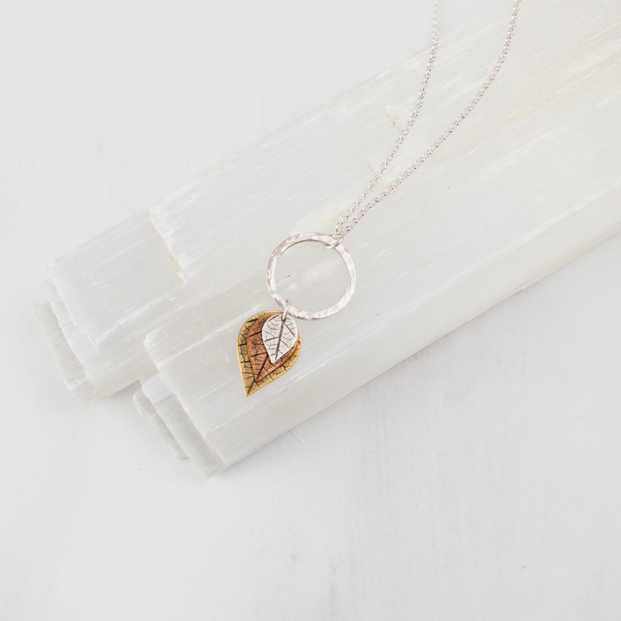 Graduated leaf necklace with sterling silver, copper, and brass leaves on white background