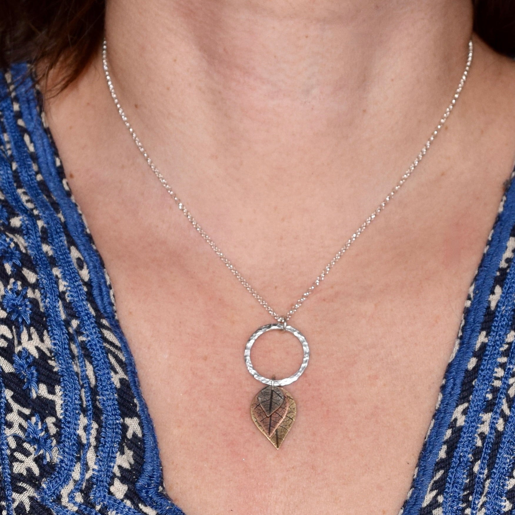 Model wearing graduated mixed metal leaf necklace on 18 inch sterling silver chain
