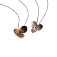 Top view of handmade botanical hydrangea bloom pendant necklaces in sterling silver and jeweler's brass, artisan nature jewelry handcrafted in Vermont