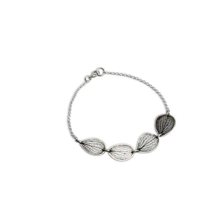 Overhead view of handmade sterling silver hydrangea petal impression bracelet, four connected petals with satin finish and patina, botanical jewelry crafted in Vermont