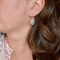 Model wearing handmade sterling silver hydrangea petal impression dangle earrings, artisan floral jewelry handcrafted in Vermont