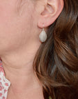 Model wearing handmade sterling silver hydrangea petal impression dangle earrings, artisan floral jewelry handcrafted in Vermont
