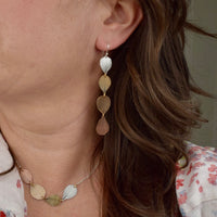 Model wearing handmade hydrangea petal ombré drop earrings in sterling silver brass bronze and copper, artisan botanical jewelry crafted in Vermont