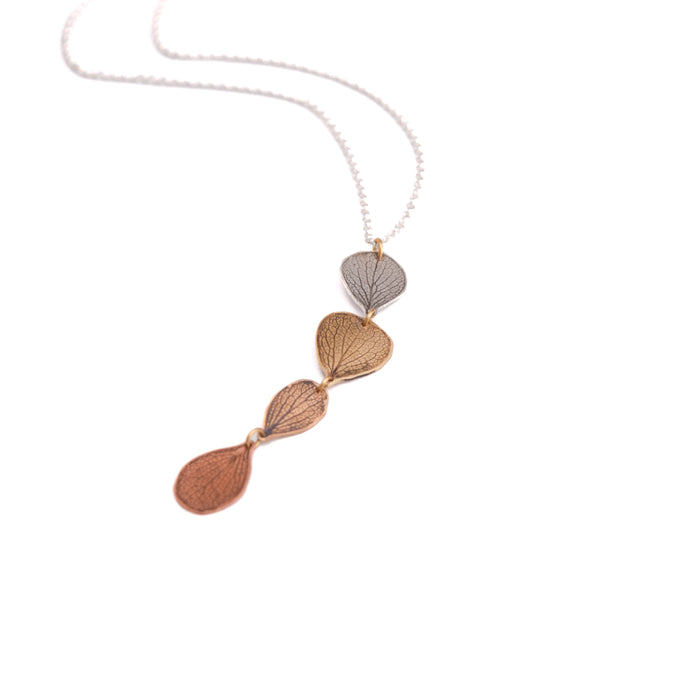 Overhead view of handmade hydrangea petal impression ombré necklace in sterling silver, jeweler's brass, bronze and copper on sterling silver chain, botanical jewelry crafted in Vermont