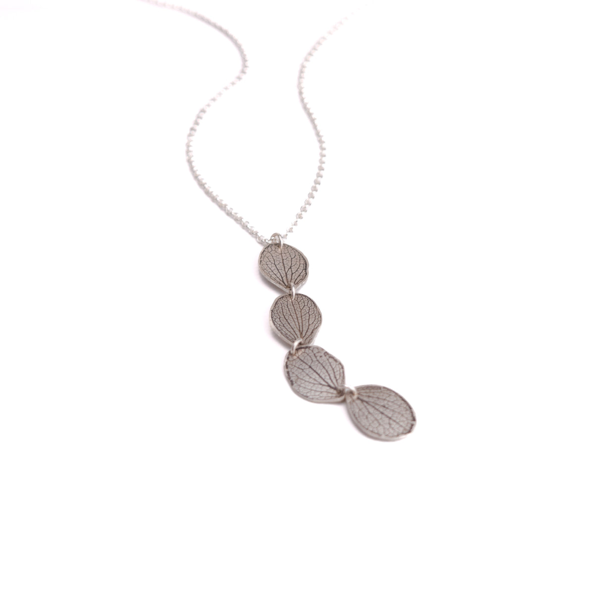 Overhead view of handmade sterling silver hydrangea petal impression pendant necklace, four connected petals with satin finish and patina, botanical jewelry crafted in Vermont