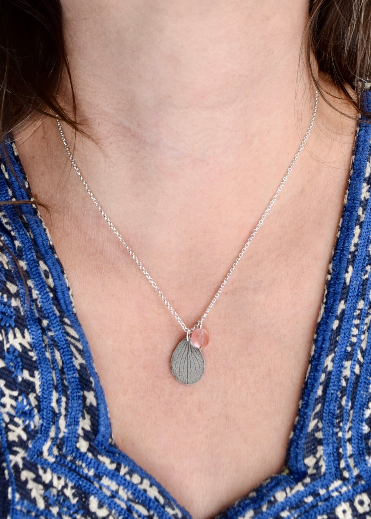 Model wearing handmade sterling silver hydrangea petal and rose quartz necklace, delicate botanical gemstone jewelry handcrafted in Vermont