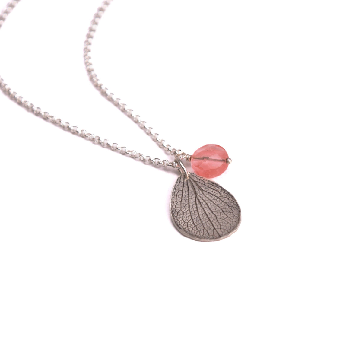 Overhead view of handmade sterling silver hydrangea petal impression necklace with faceted rose quartz bead, botanical gemstone jewelry crafted in Vermont
