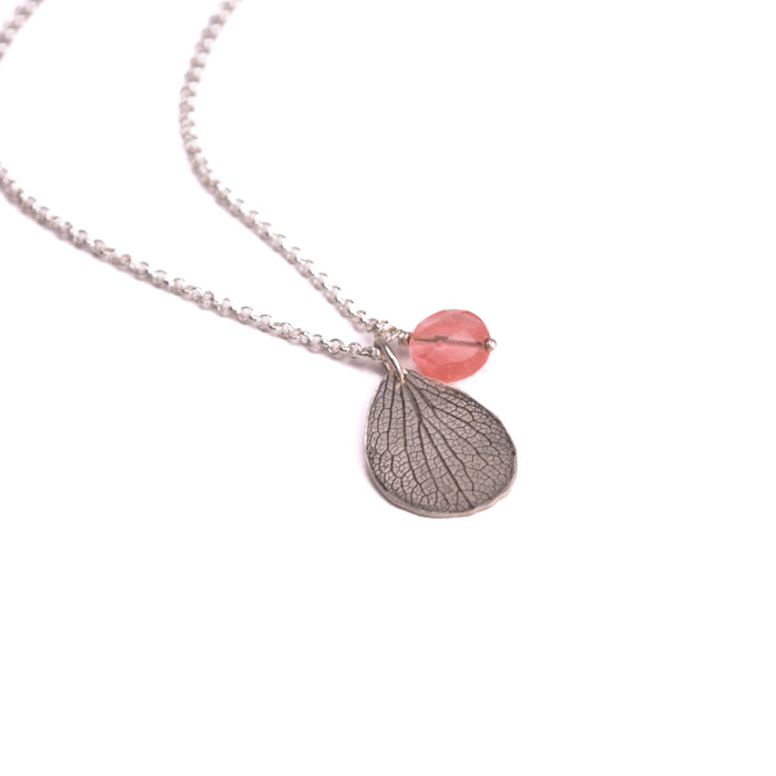 Overhead view of handmade sterling silver hydrangea petal impression necklace with faceted rose quartz bead, botanical gemstone jewelry crafted in Vermont