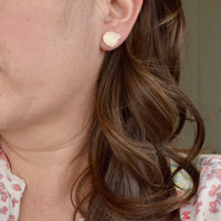 Model wearing handmade jeweler's brass hydrangea petal impression stud earrings, nature inspired botanical jewelry handcrafted in Vermont