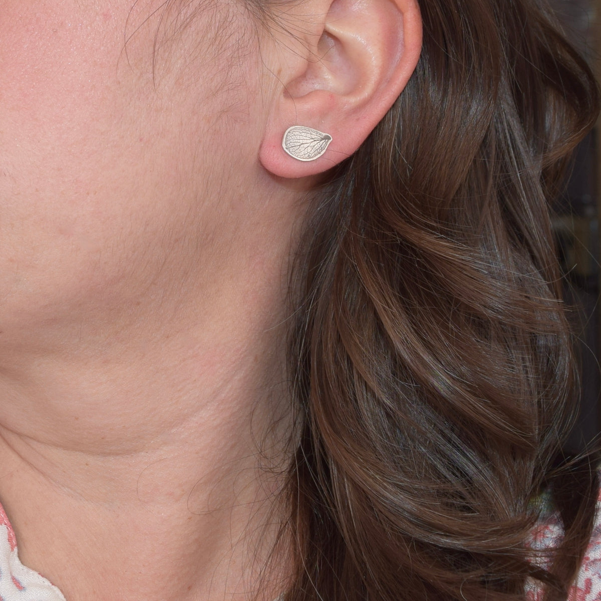 Model wearing handmade sterling silver hydrangea petal impression stud earrings, delicate floral jewelry handcrafted in Vermont