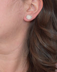 Model wearing handmade sterling silver hydrangea petal impression stud earrings, delicate floral jewelry handcrafted in Vermont