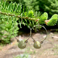 Handmade sterling silver hoop earrings with genuine faceted lemon jade briolette and brass wire wrapping displayed on pine tree branch, artisan gemstone jewelry crafted in Vermont