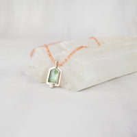 Close-up of bright polish sterling silver setting around a mint green kyanite gemstone pendant
