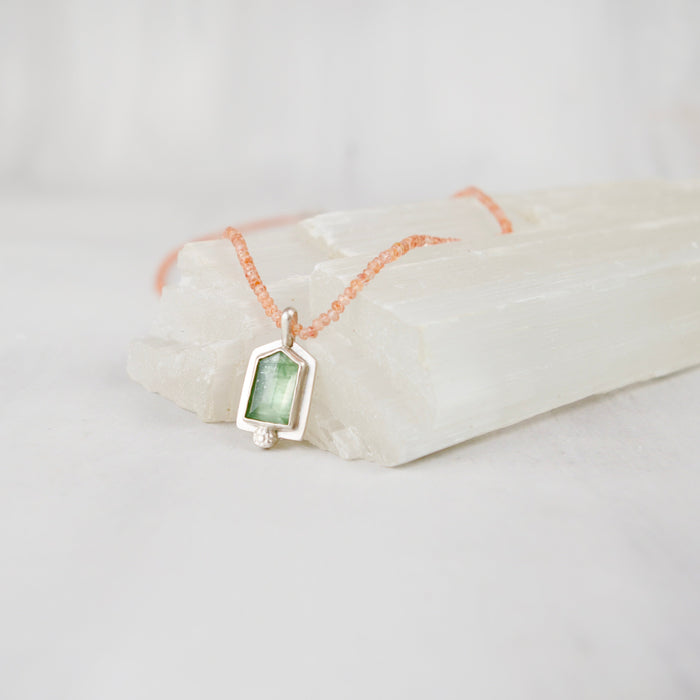 Close-up of bright polish sterling silver setting around a mint green kyanite gemstone pendant