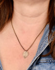 Model wearing jeweler's brass botanical leaf necklace with black patina, delicate nature jewelry handcrafted in Vermont