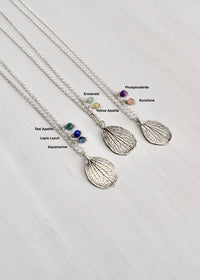 Overhead view of handmade sterling silver hydrangea mother petal necklaces showing available gemstone options including aquamarine, lapis lazuli, teal apatite, yellow apatite, emerald, sunstone and phosphosiderite