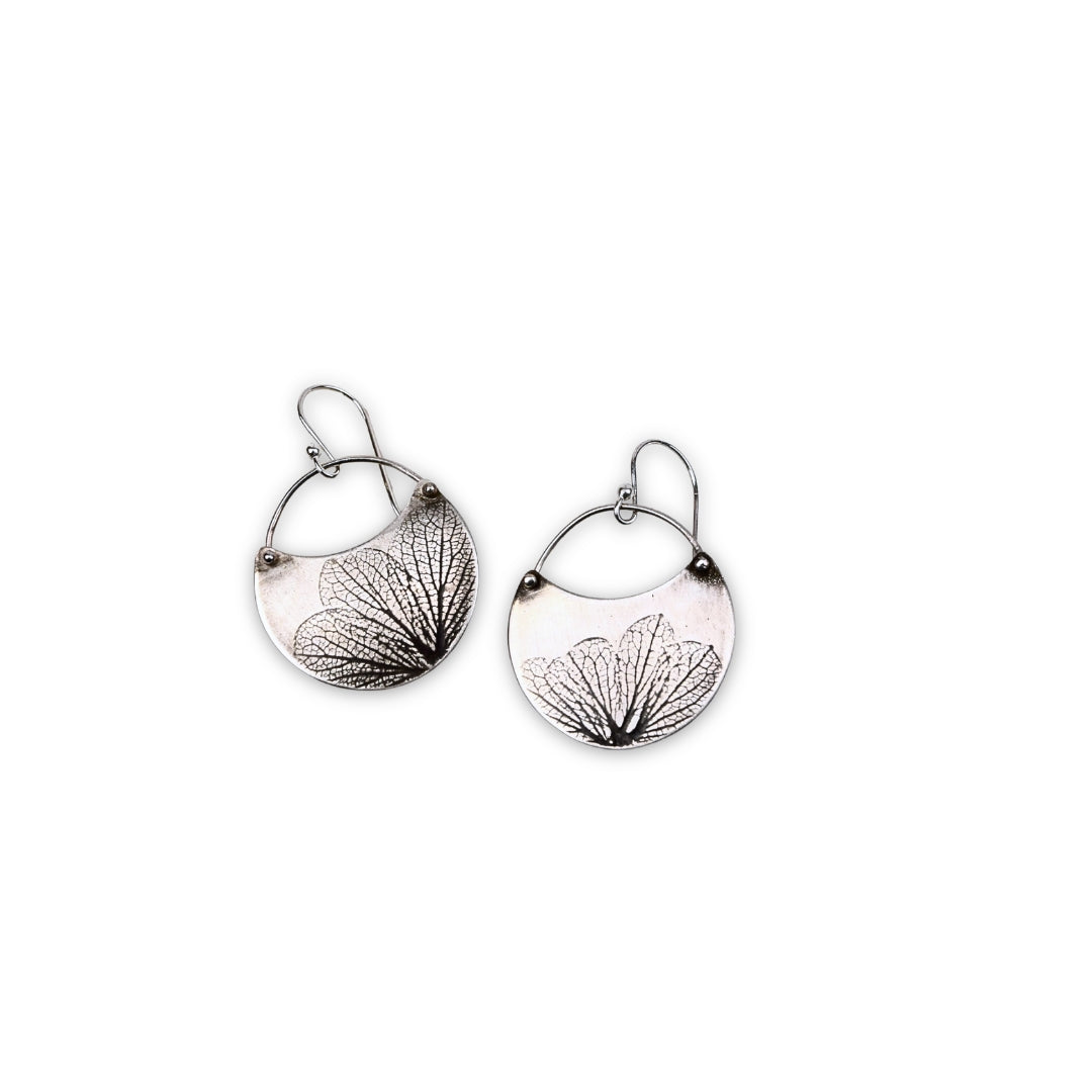 Overhead view of small handmade sterling silver hydrangea flower impression crescent dangle earrings, botanical jewelry crafted in Vermont